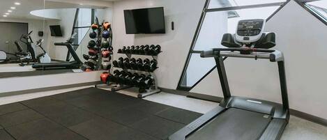 A gym with treadmills, dumbbells, and exercise equipment.
