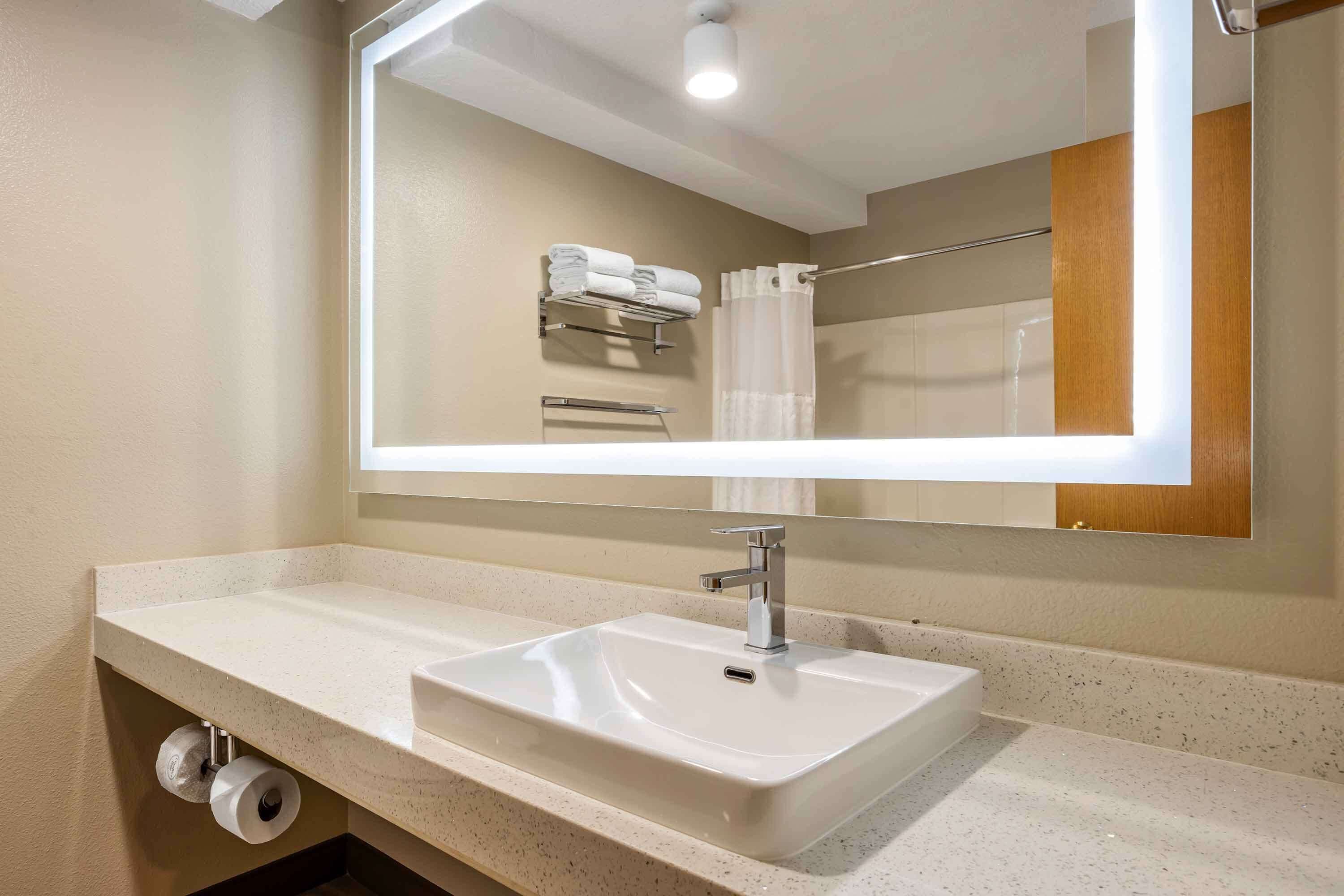 A bathroom with a white sink, a mirror, and a towel rack.