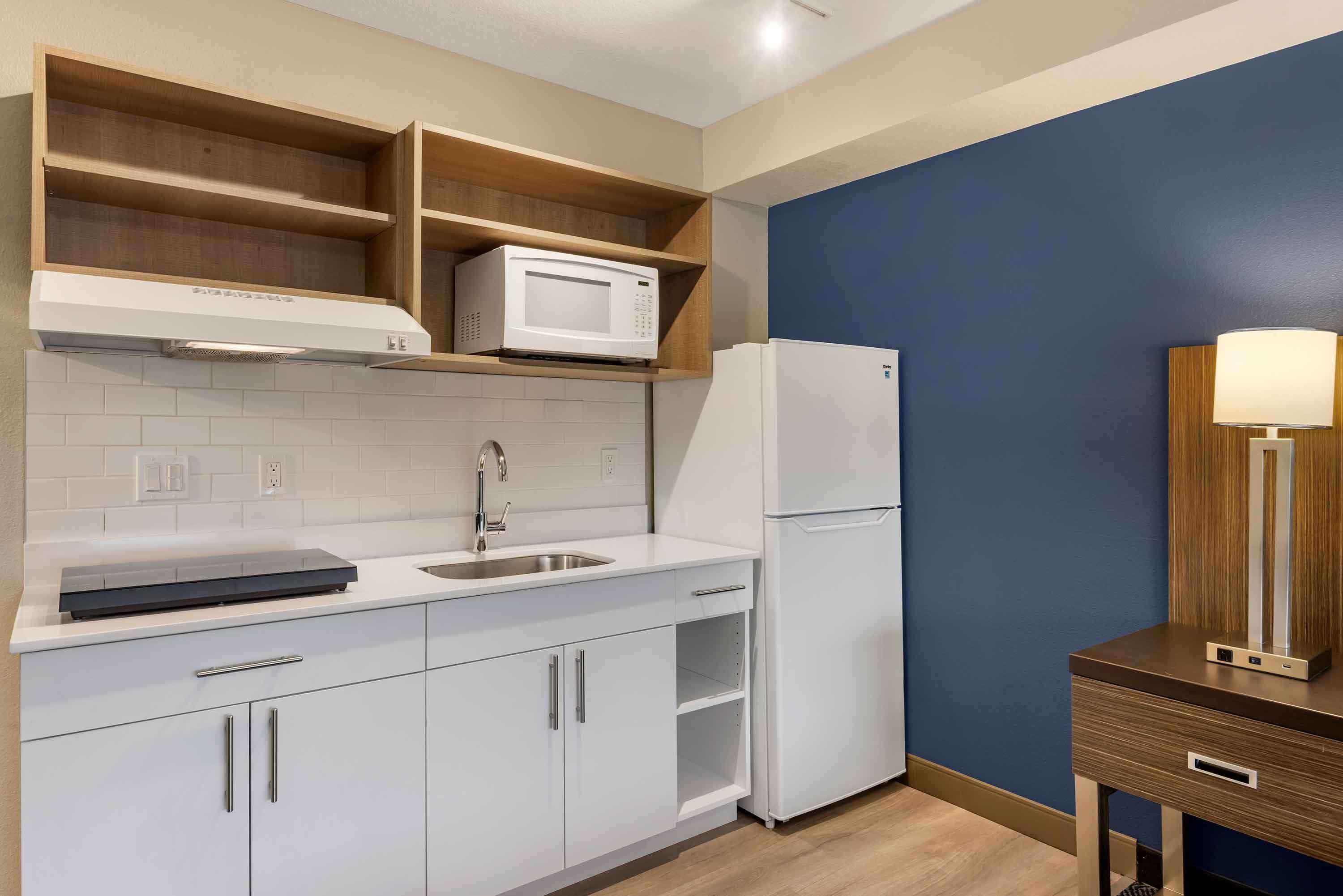 A modern kitchen with white cabinets, a microwave, and a refrigerator.