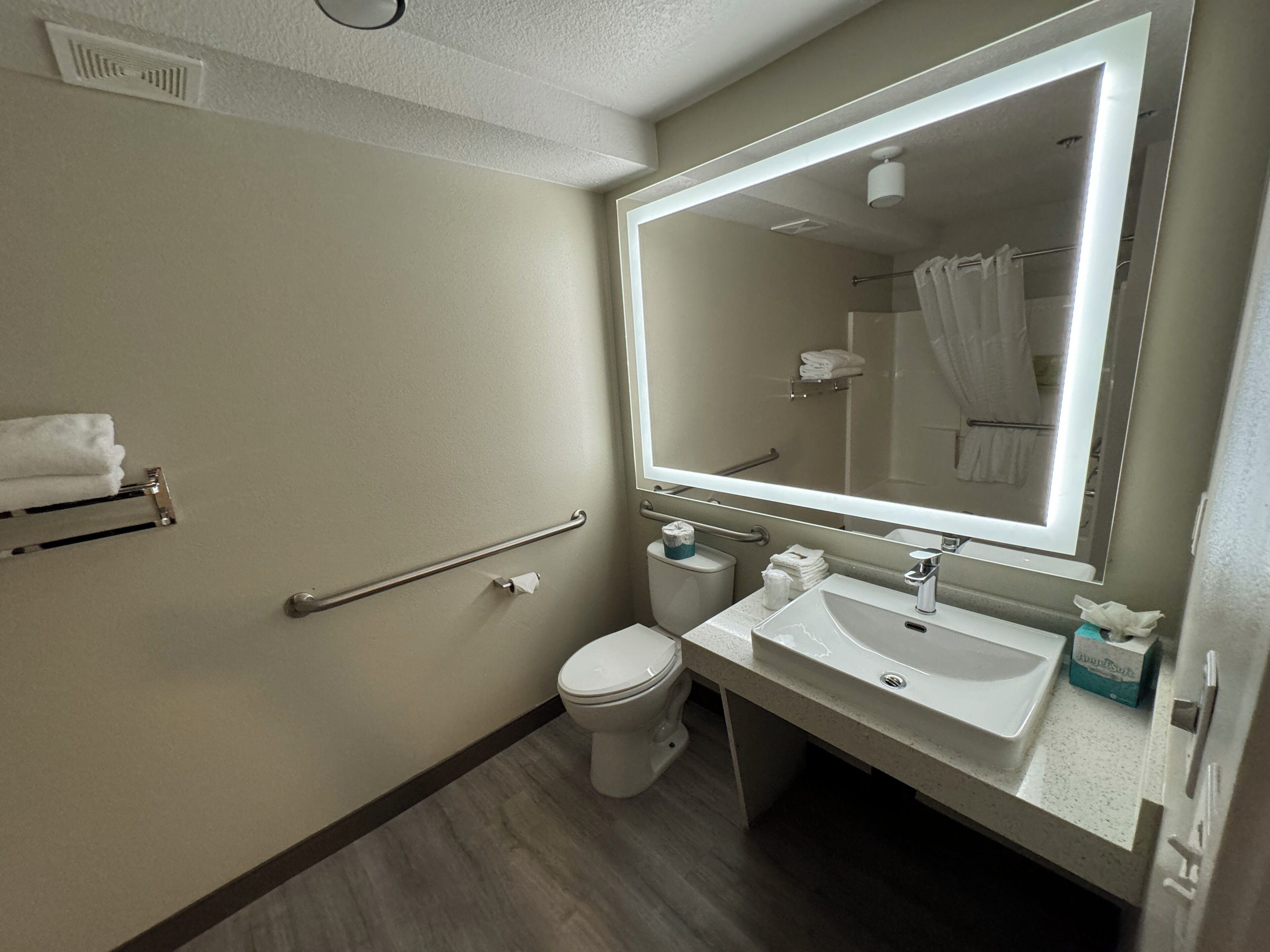 A bathroom with a toilet, sink, and mirror.
