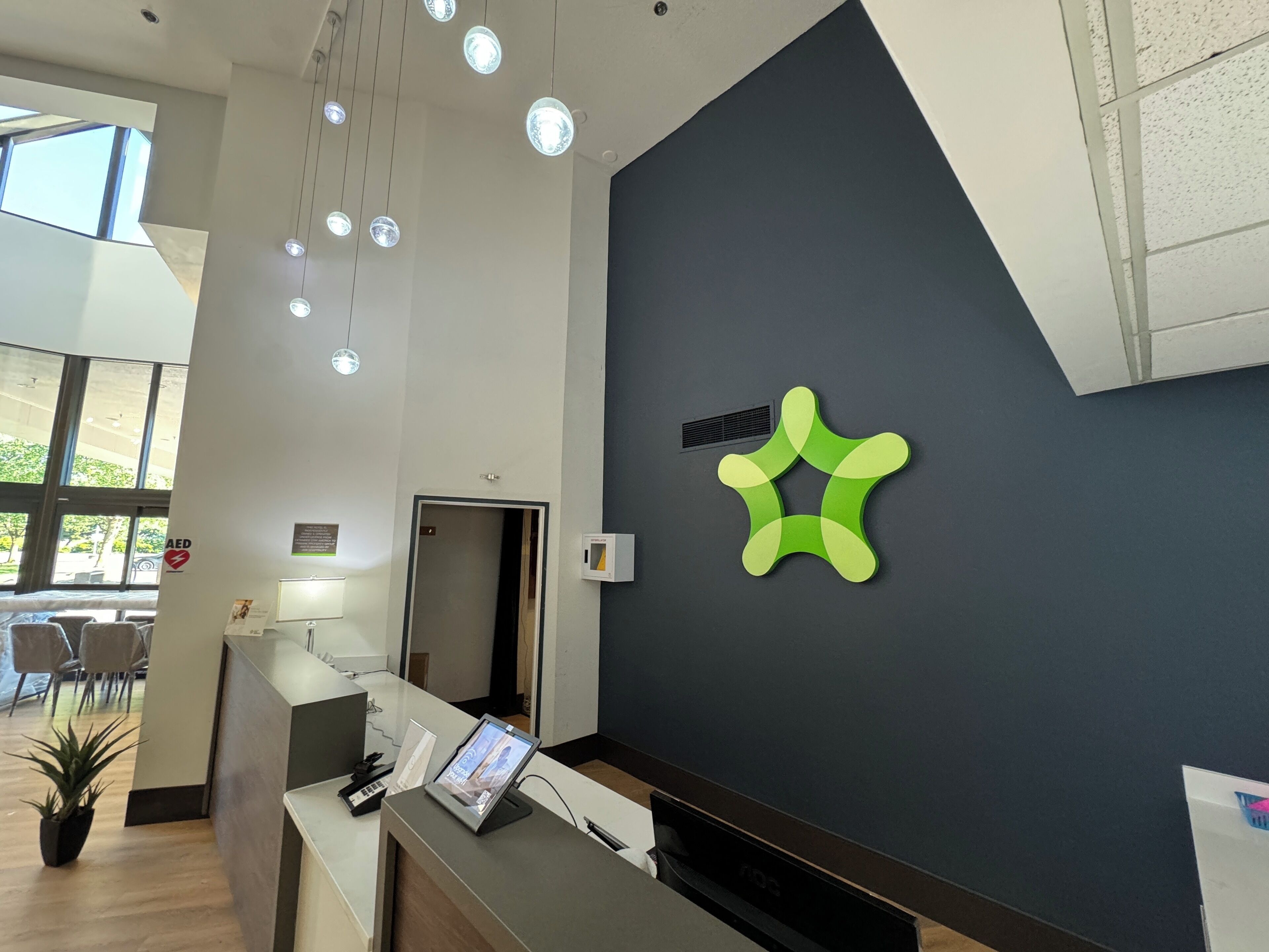 Un área de recepción de diseño moderno, que incluye un mostrador de recepción, un amplio ventanal y una original pieza de arte mural verde.