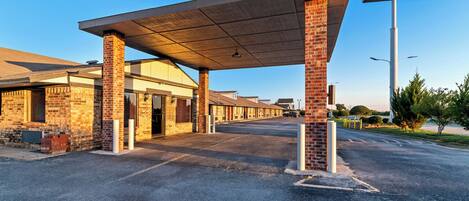 A Scottish Inn with a covered parking area, brick buildings, and a clear sky.