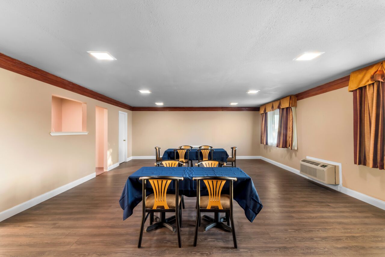 Une salle de conférence avec une longue table et des chaises, des murs de couleur beige, des boiseries et un plafond doté d’un éclairage encastré.
