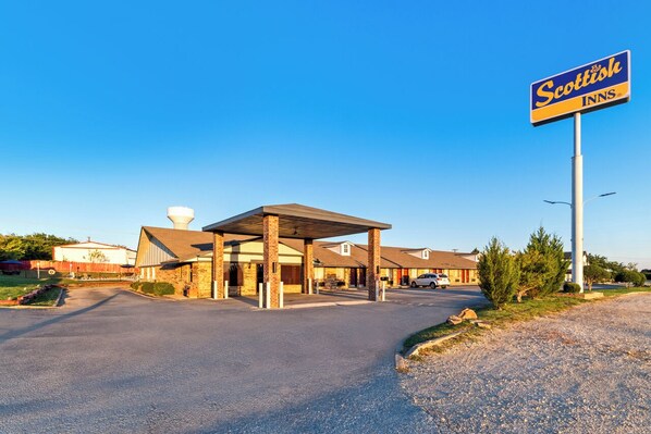 A Scottish Inn with a covered parking area, a large sign, and a building with a sloped roof. - Scottish Inn Decatur (Decatur)