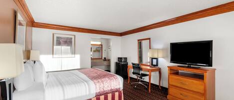 A hotel room with a bed, desk, television, and a mirror.