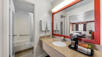 A bathroom with a bathtub, a sink, a coffee maker, and a tray with toiletries.