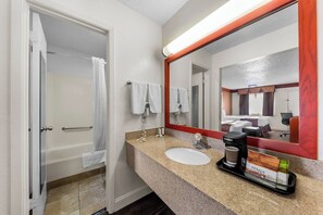 A bathroom with a bathtub, a sink, a coffee maker, and a tray with toiletries.