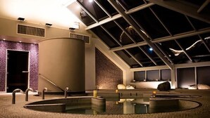 A spa area with a large central water feature, a skylight, and a stone wall.
