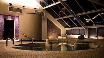 Relax in a serene spa area with a large hot tub, surrounded by a carpeted floor and a textured pattern on the walls.