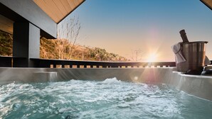 A hot tub with a view of a sunset and a mountain in the background.