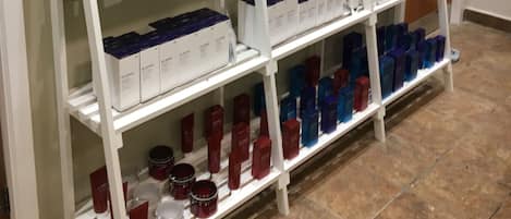Una estantería blanca con varios productos, incluyendo cajas y botellas, en un entorno comercial.