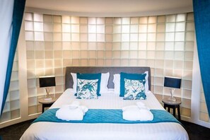 Une chambre d’hôtel avec un grand lit, deux tables de chevet et une fenêtre avec des rideaux.