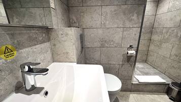 Un baño moderno con lavamanos blanco, inodoro y zona de ducha.