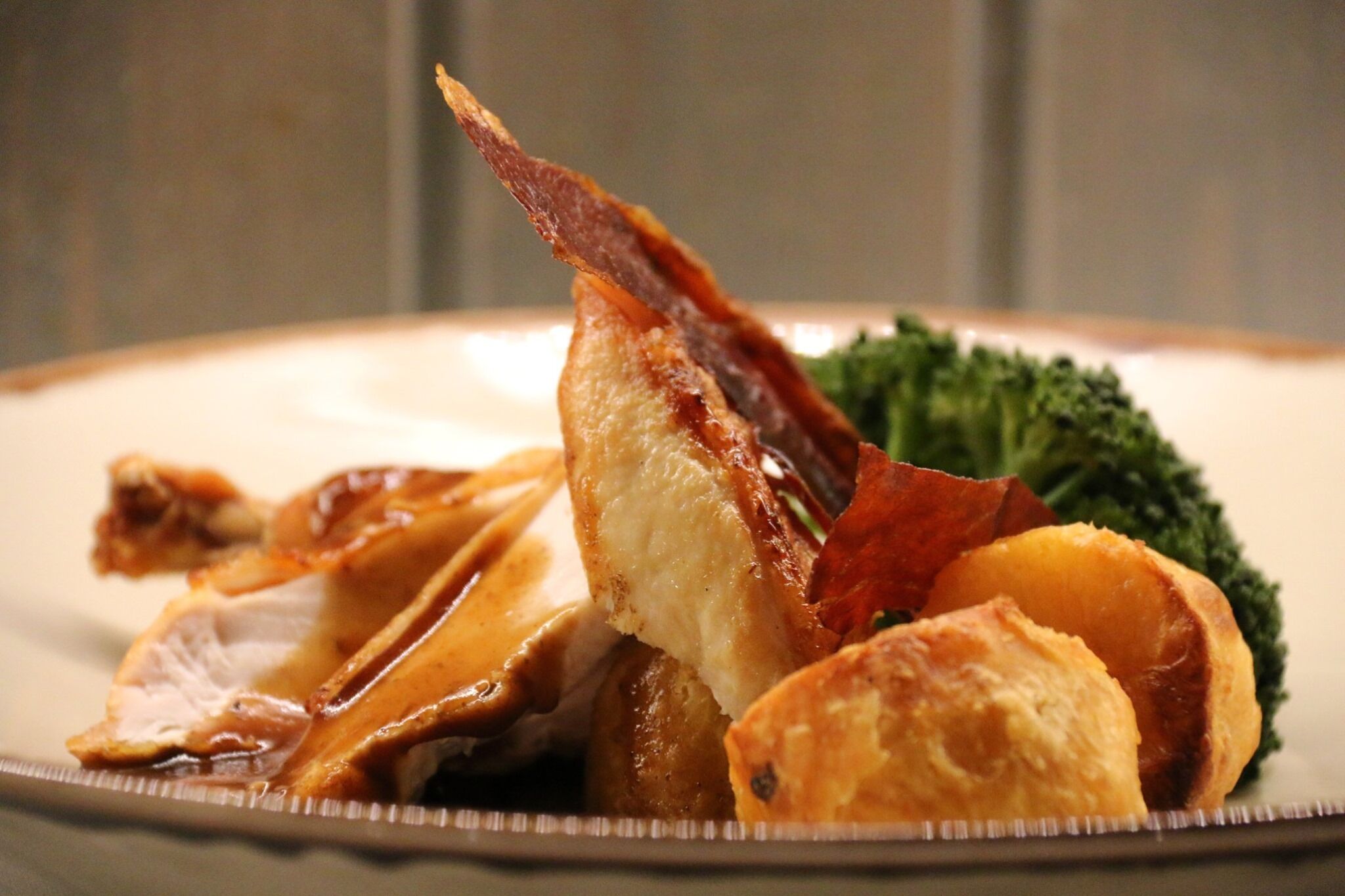 A plate with roasted meat, vegetables, and a piece of bread.
