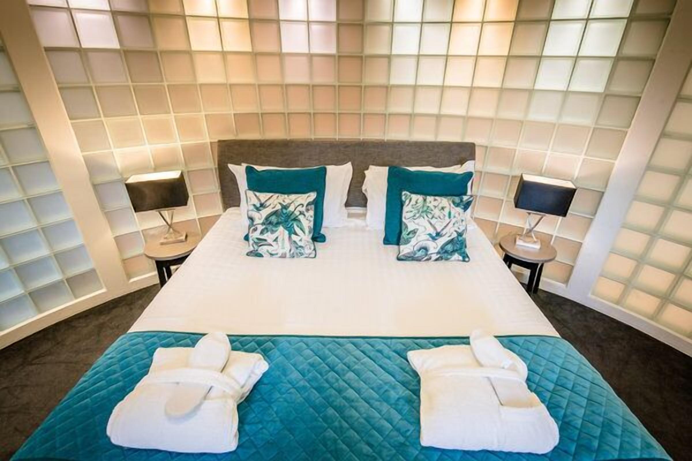 Une chambre d’hôtel avec un grand lit, deux tables de chevet et une tête de lit.