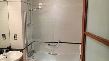 Un baño con ducha de vidrio, bañera y lavamanos.