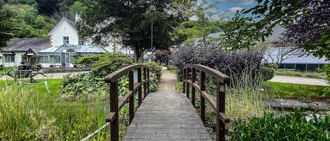 Un puente de madera que lleva a un edificio blanco con techo verde.