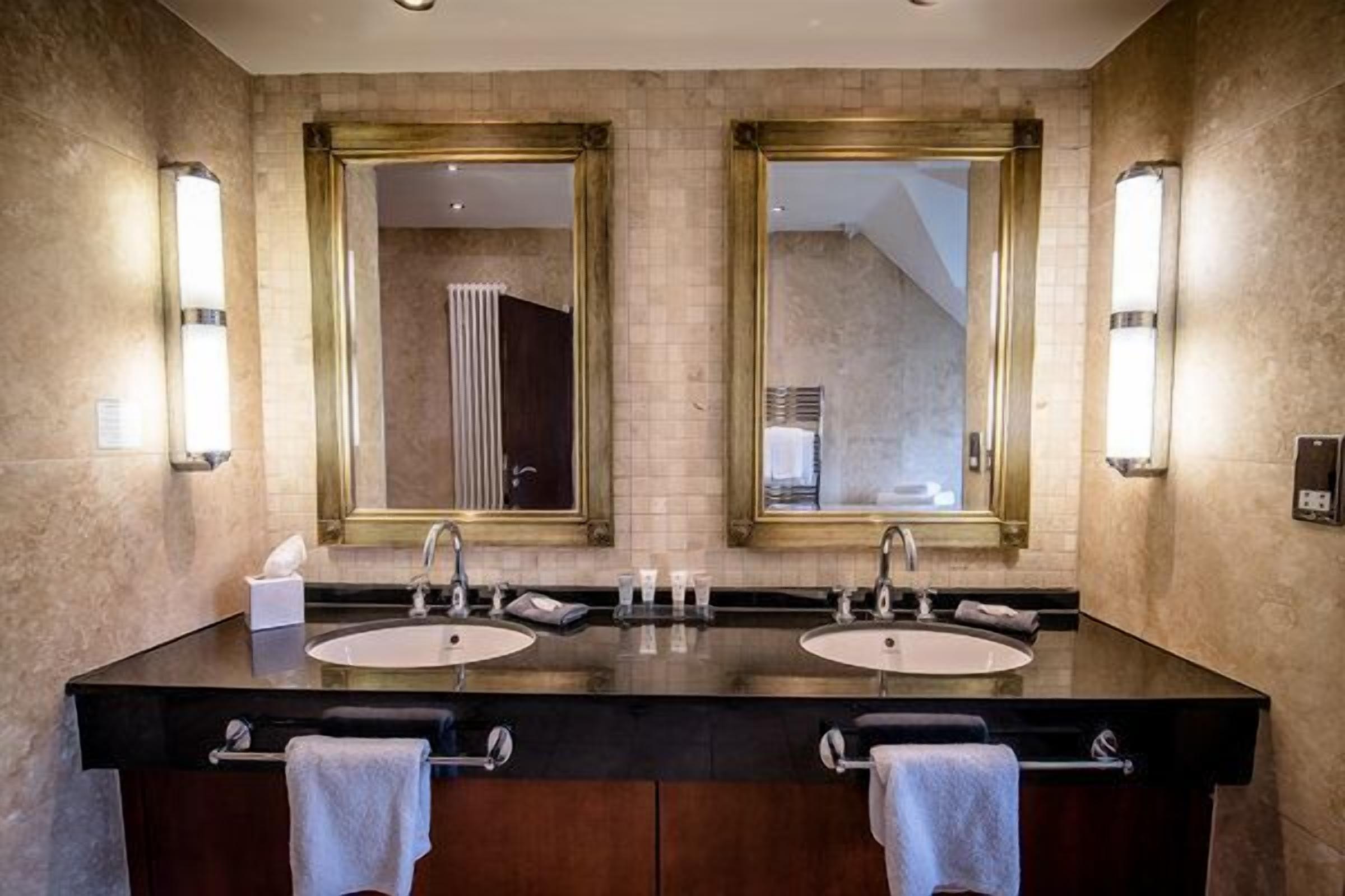 A modern bathroom with two sinks, large mirrors, and towel racks.