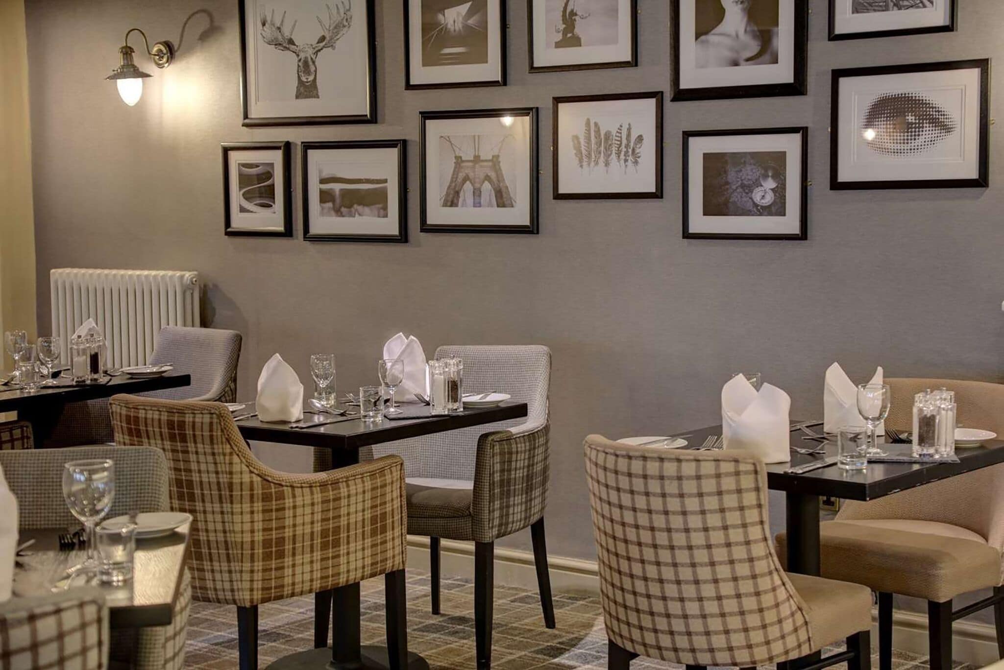 A dining area with checkered chairs, tables set with plates, glasses, and cutlery.
