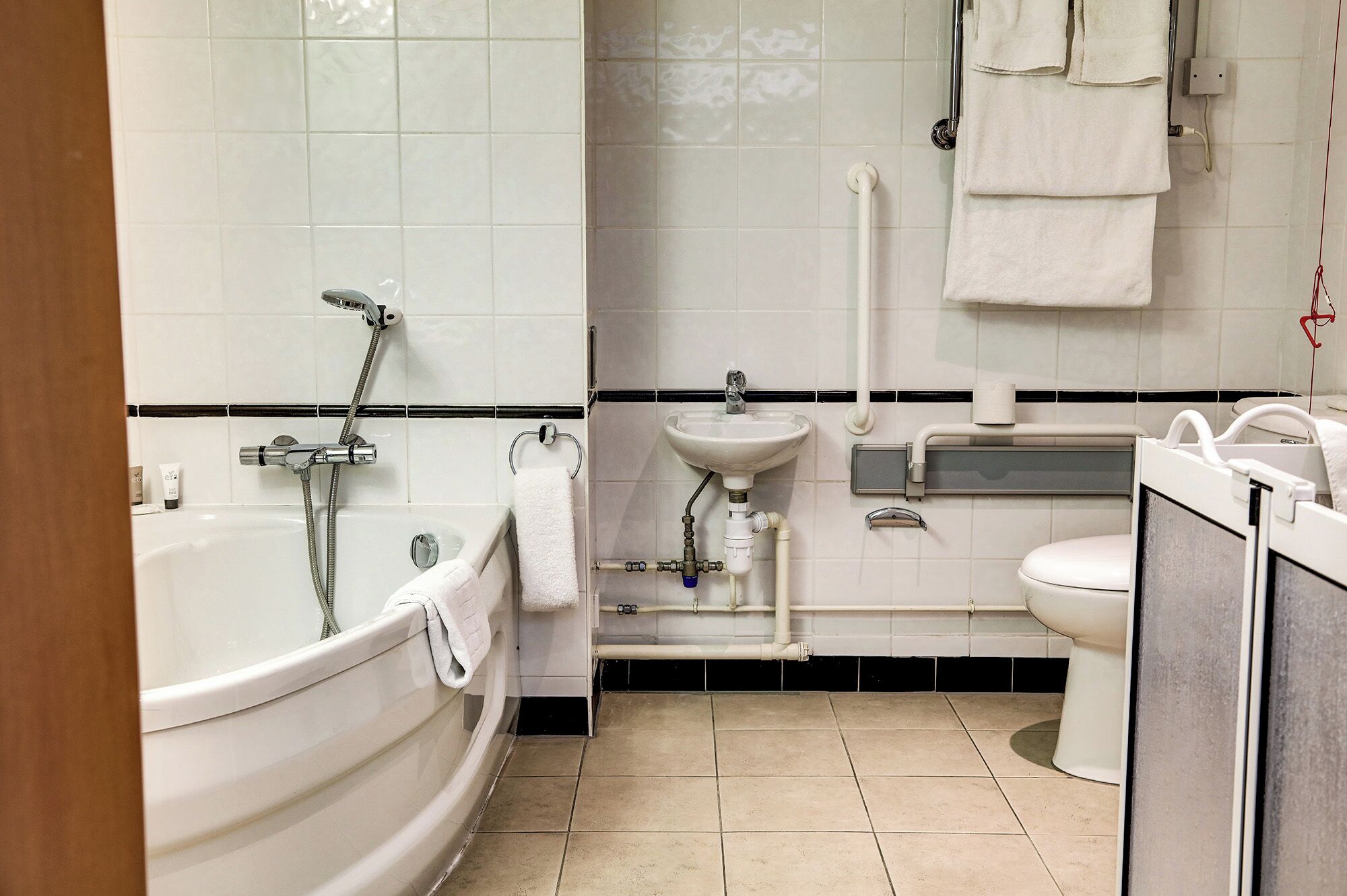 A modern bathroom with a bathtub, toilet, sink, and towel rack.