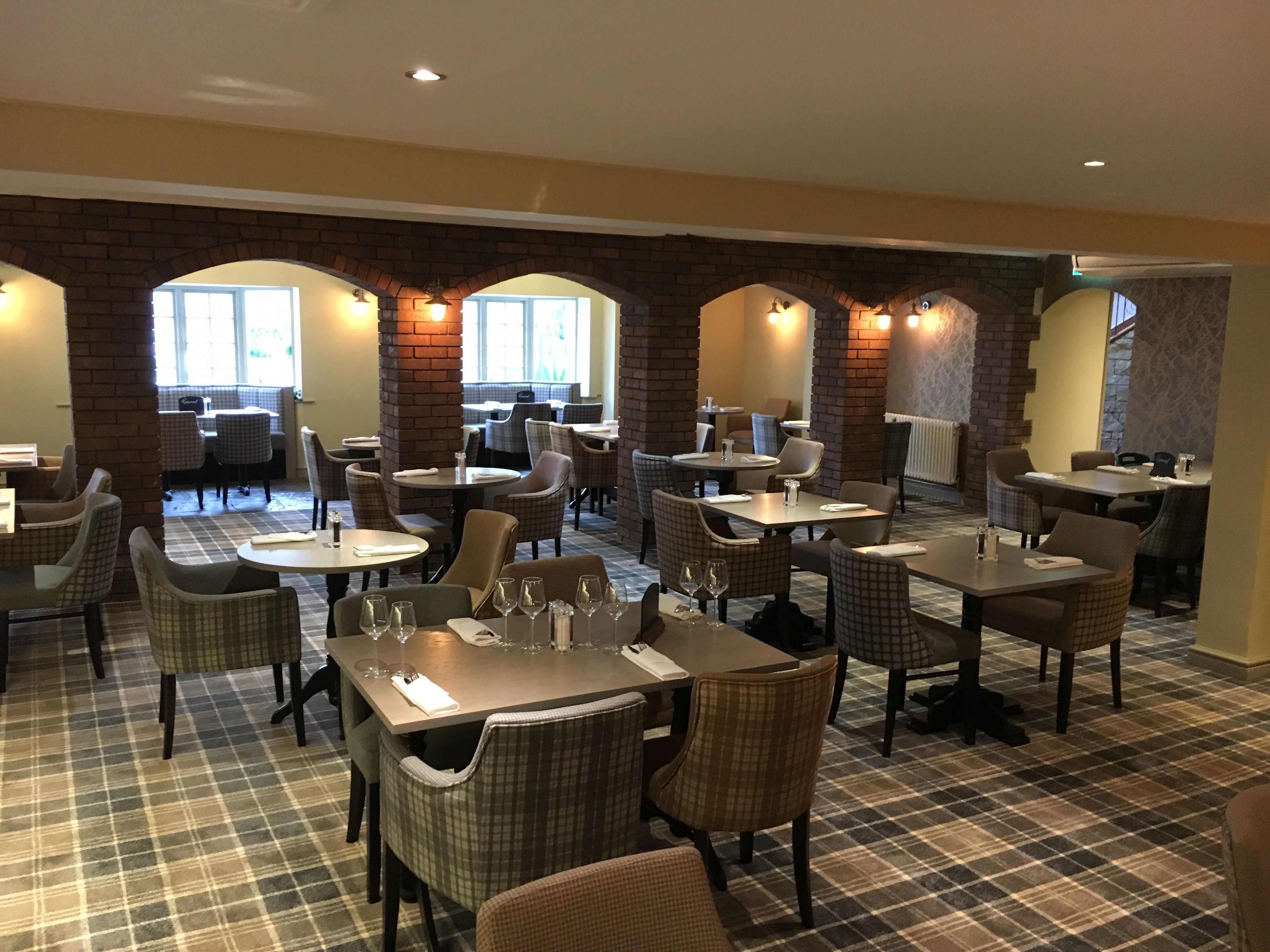 A restaurant with checkered flooring, brick arches, and multiple dining tables and chairs.