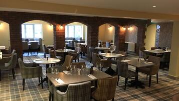 Un restaurant doté d’un sol à carreaux, d’arcs en briques et de nombreuses tables et chaises.