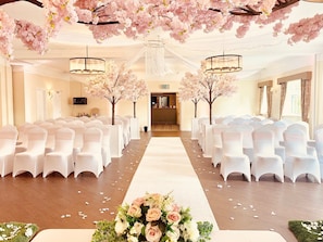 Intimate wedding ceremonies take place in this elegant space, surrounded by rows of white chairs and a stunning floral arrangement.