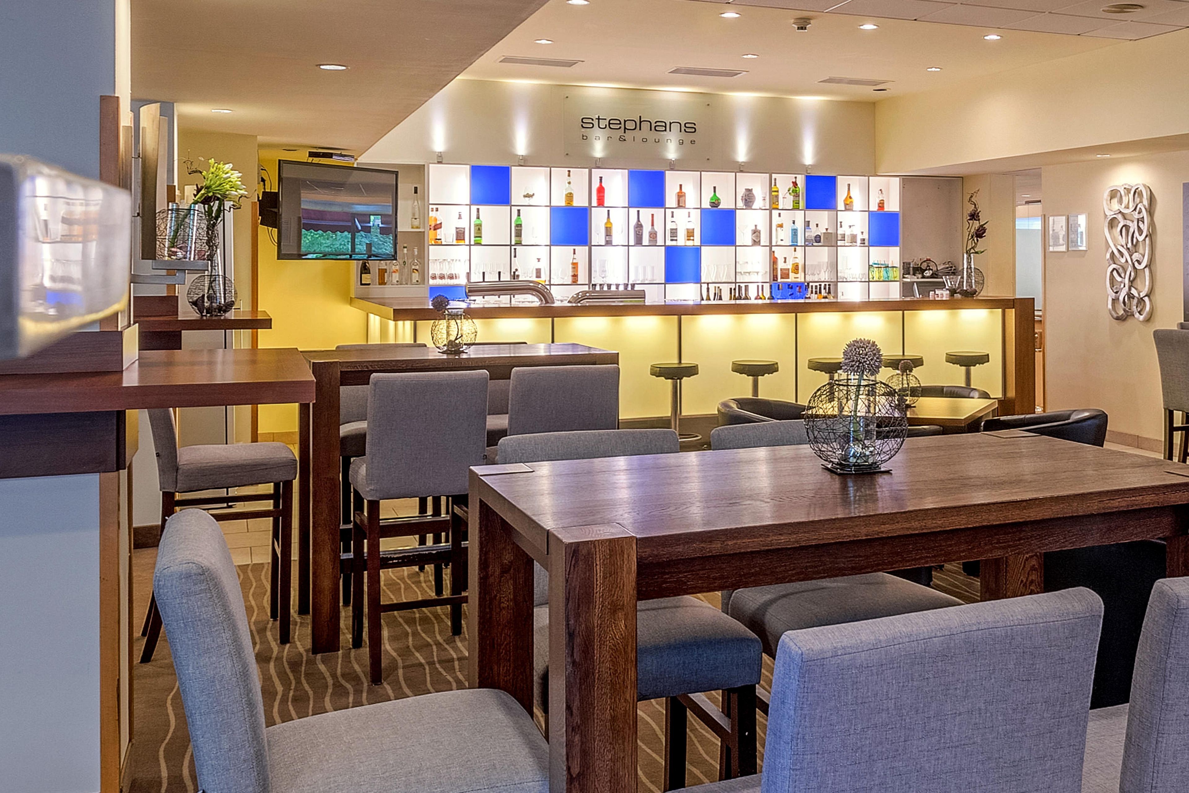 Un área de bar o sala de estar con barra, asientos y una pantalla de televisión.