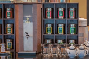 Mostrador de una cafetería con diversos productos de té y café, incluyendo latas y tazas de vidrio.
