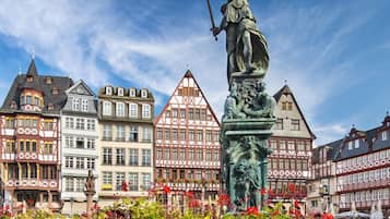 Eine Statue einer Frau, die Waage und Schwert hält, umgeben von farbenfrohen Fachwerkhäusern.