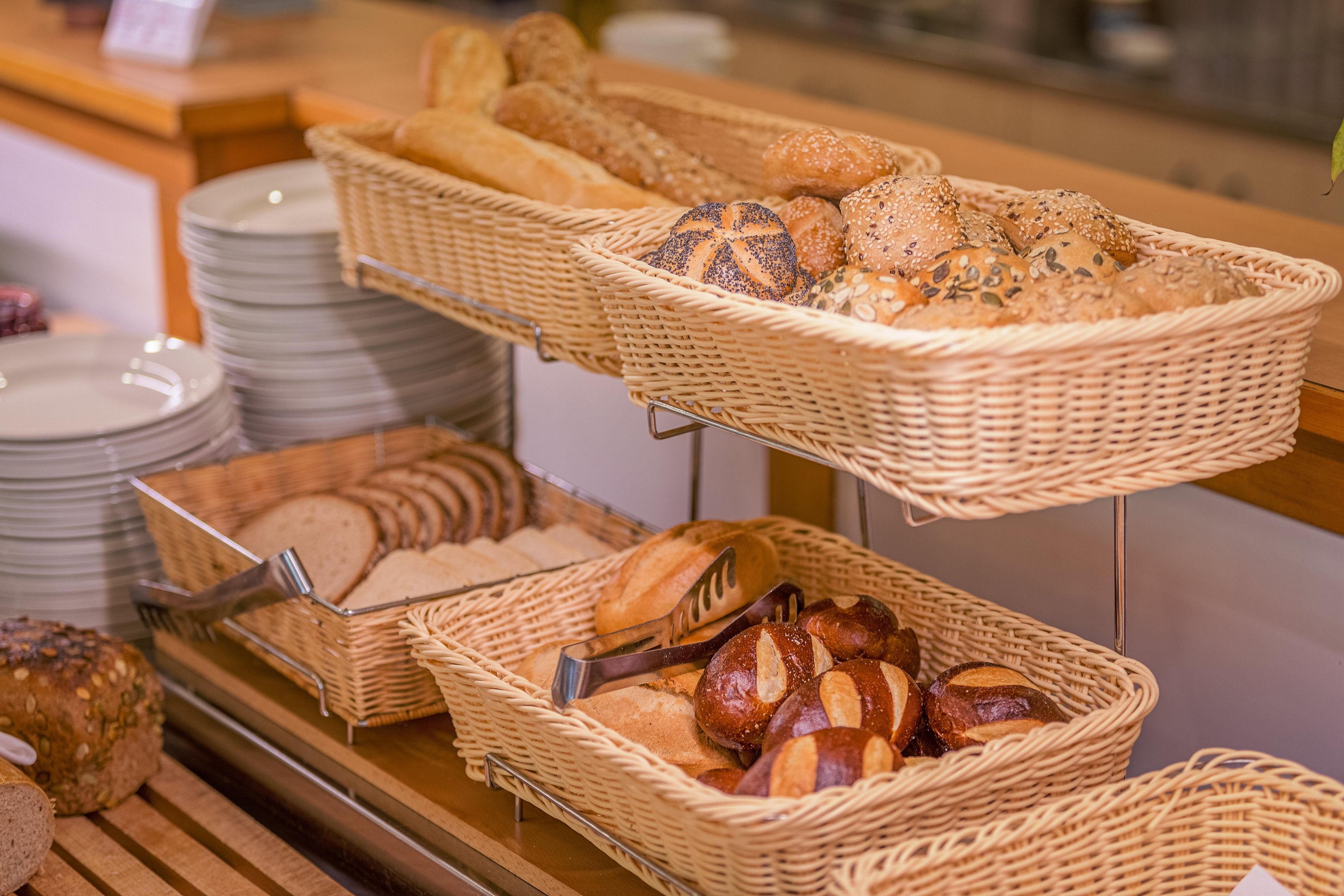 Un espositore di panetteria con diversi tipi di pane e dolci in cesti di vimini.