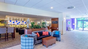 Eine moderne Lobby mit Barbereich, Sitzgelegenheiten und einer Rezeption.