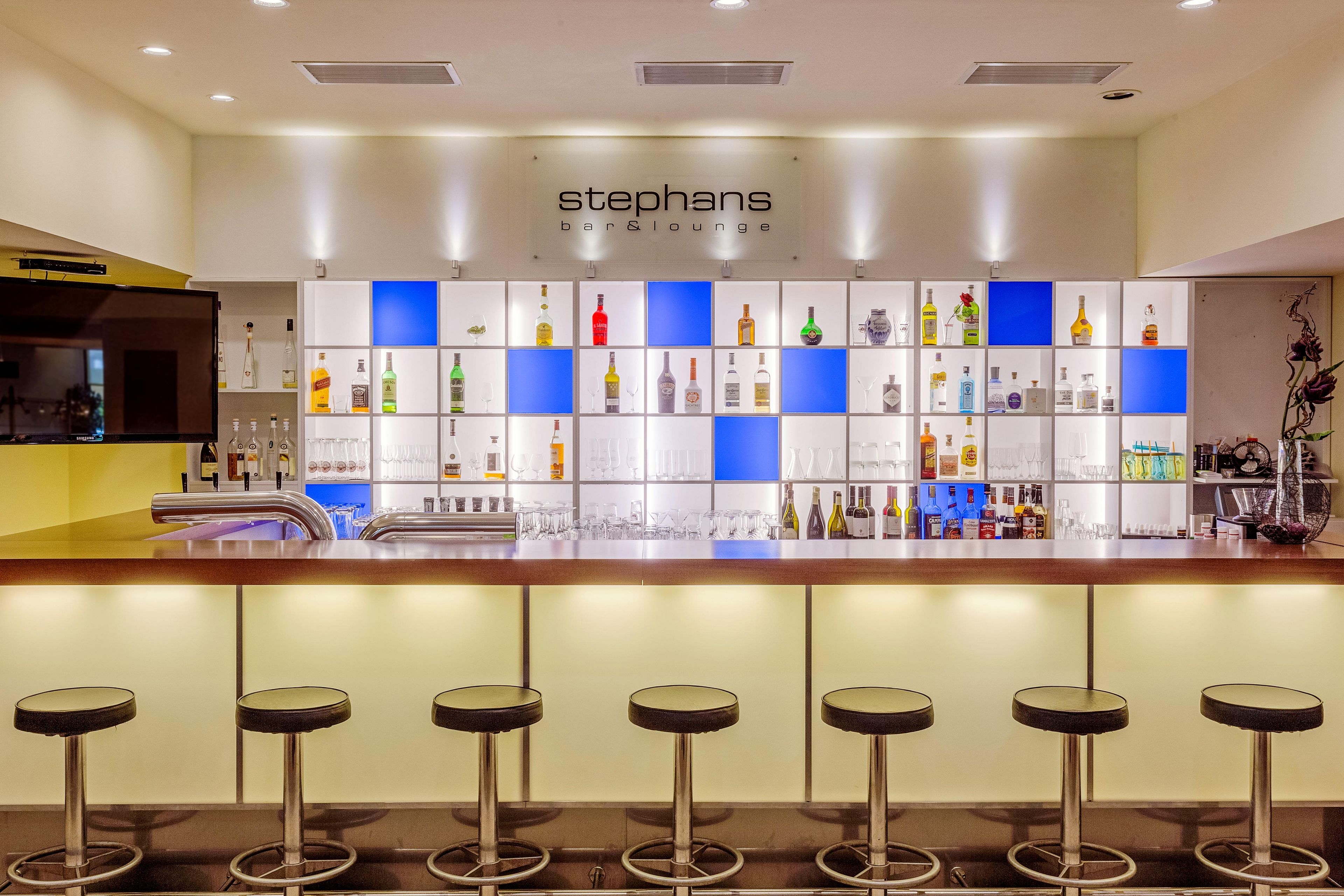 Un espace bar avec une enseigne portant le nom « stphans », ainsi qu’une variété de bouteilles d’alcool et de verres.