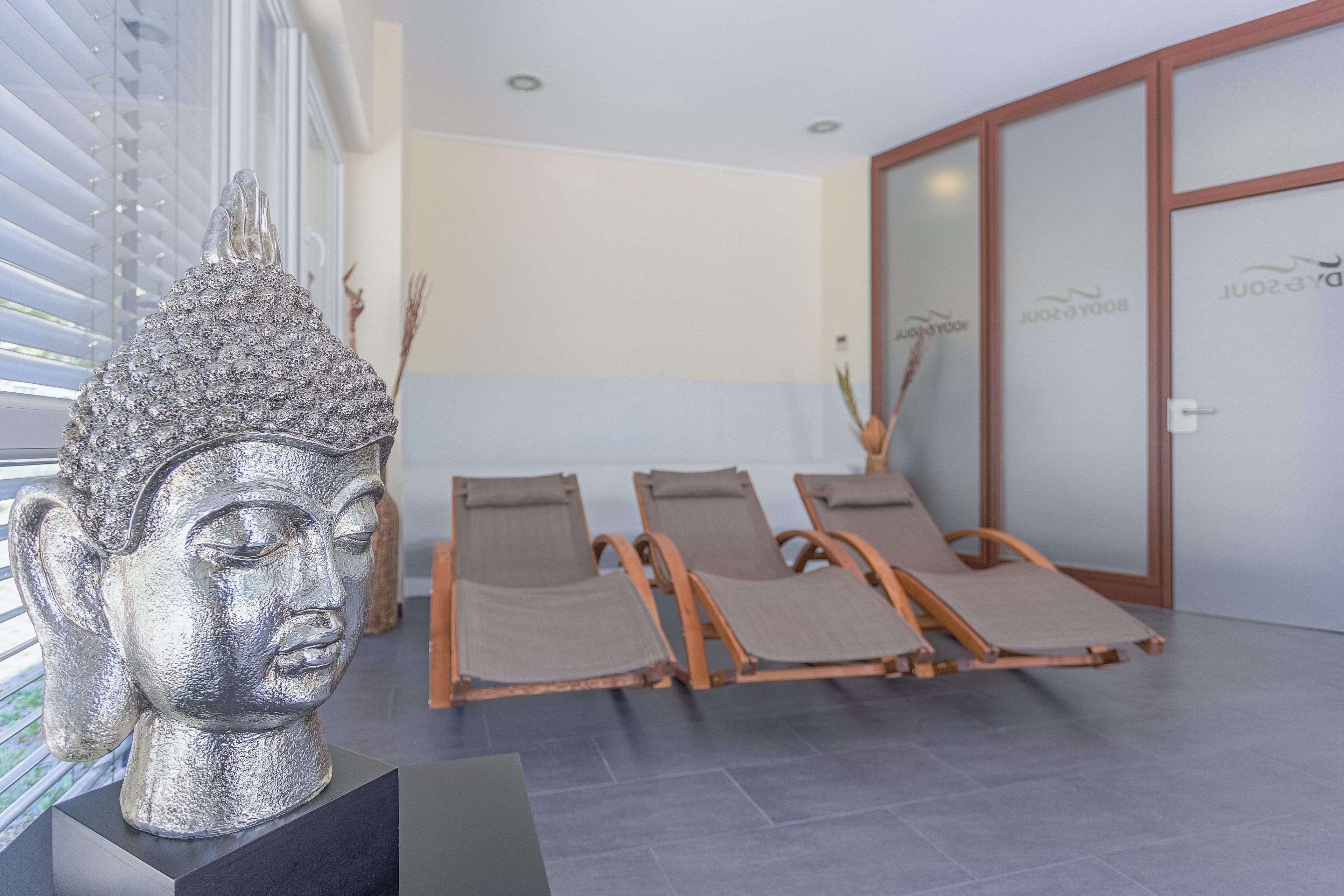 A modern interior with a statue, reclining chairs, and a reception area.