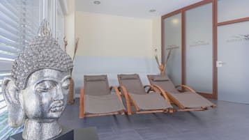 A modern interior with a statue, reclining chairs, and a reception area.