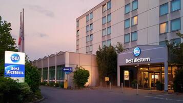 L'ingresso di un hotel con la segnaletica Best Western, un cartello per il parcheggio e un'asta con bandiera.