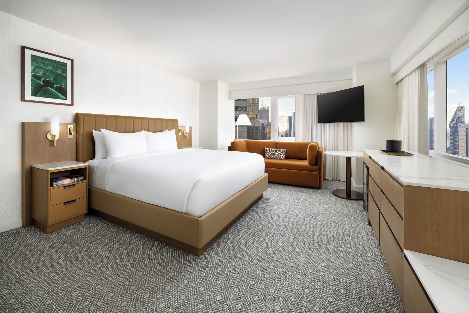 Ein Hotelzimmer mit einem großen Bett, einer Sitzecke, einem Fernseher und Blick auf die Stadt.