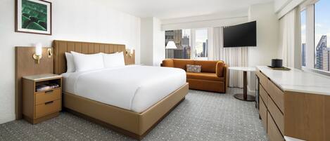 Habitación de hotel con una cama grande, un sofá, un televisor y vistas a la ciudad.