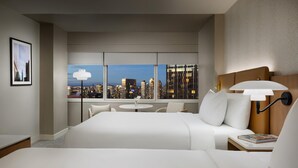 Ein Hotelzimmer mit einem großen Bett, einem runden Tisch und Blick auf die Stadt.