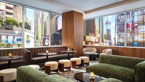 Eine moderne Lounge mit Sitzgelegenheiten, Tischen und großen Fenstern mit Blick auf die Stadt.