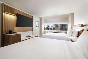 Two large beds with white linens, a flat-screen TV, and a desk for work or reading.