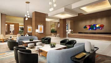 Un hall d’hôtel moderne, doté d’espaces aménagés avec des sièges, d’un comptoir de réception et d’œuvres d’art accrochées aux murs.