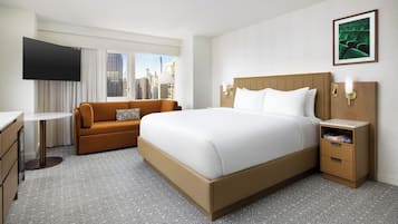 Una habitación de hotel con una cama grande, un sofá, un escritorio y una televisión.