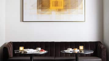 Een moderne woonkamer met een donkerbruine bank, drie bijpassende voetenbankjes, een salontafel en een abstract kunstwerk in een lijst aan de muur.
