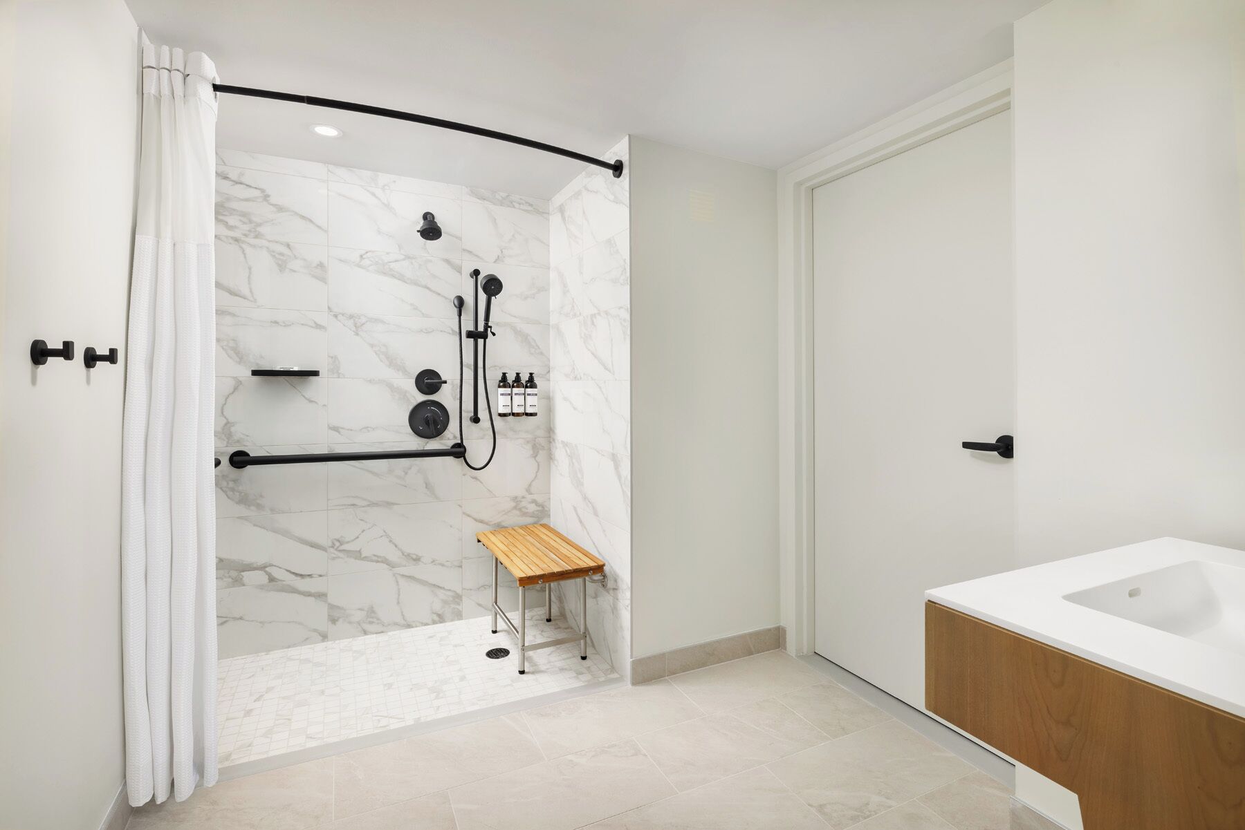 A modern bathroom with a shower, a wooden bench, and a white bathtub.