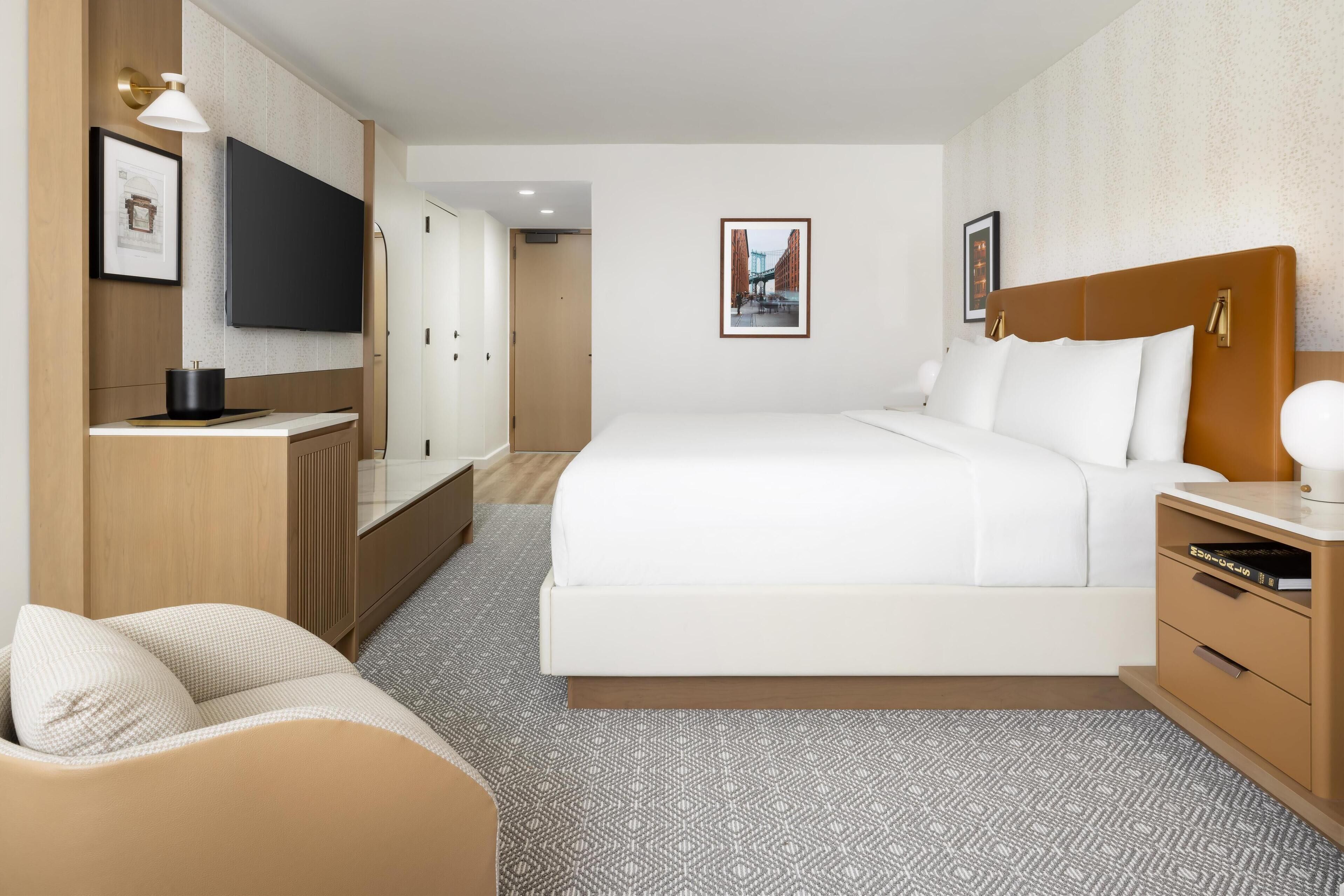Habitación de hotel con una cama grande, televisor montado en la pared, escritorio con una silla y un armario.
