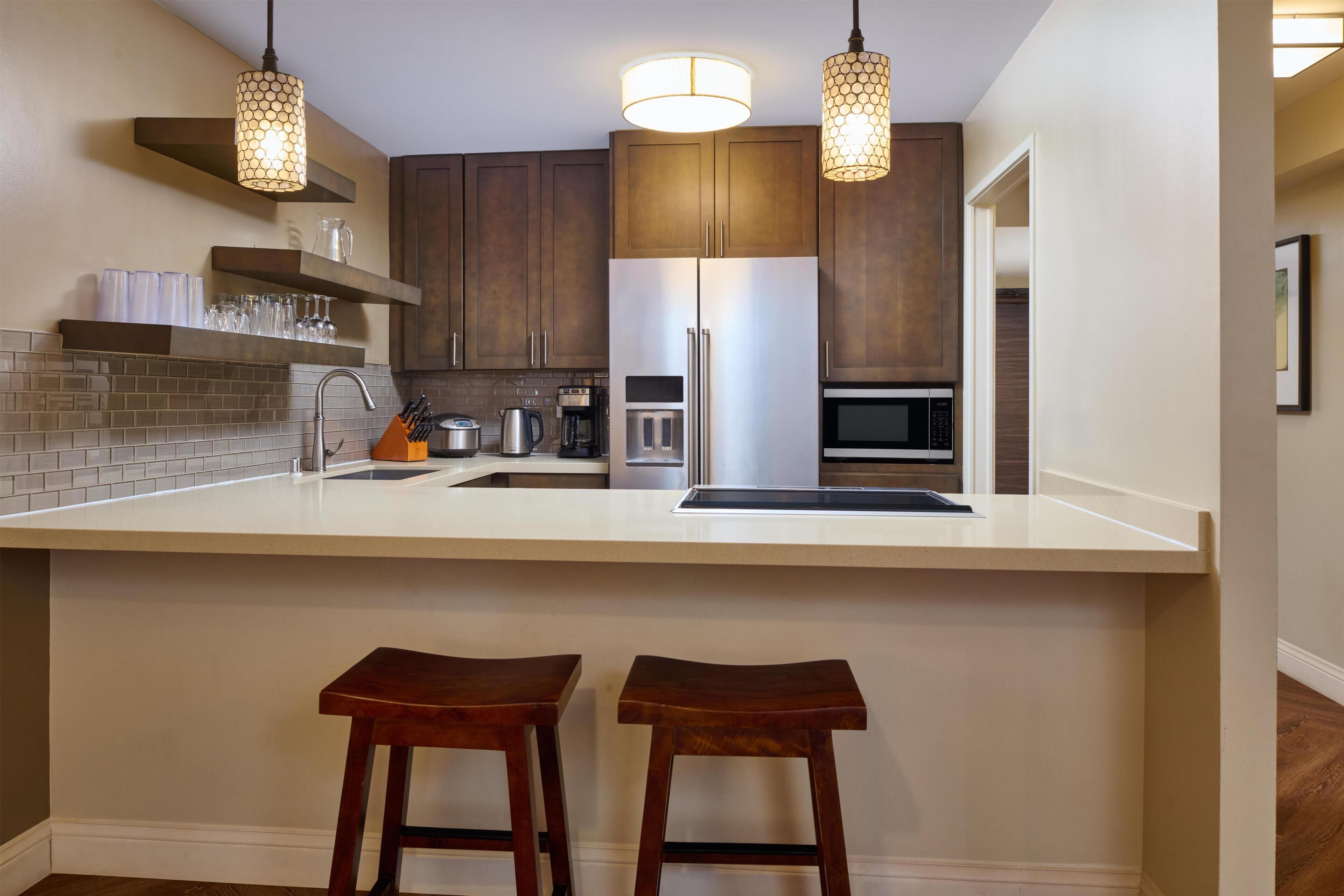 A kitchen with a central island, stainless steel appliances, and pendant lighting.