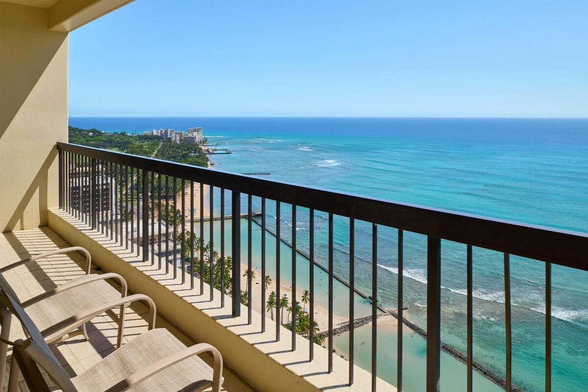 A balcony with a view of the ocean and a beach.