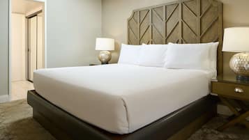 A neatly made bed with a headboard, a bedside table with a lamp, and a carpeted floor.