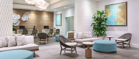 A modern reception area with a reception desk, seating arrangements, and a large plant.